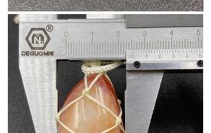 Detail showing red agate stone pendant width measurement of 24mm using a caliper