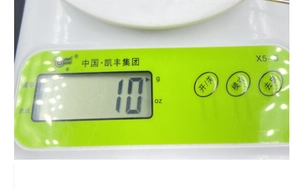 Detail of white kitchen scale control panel with LCD display and green buttons