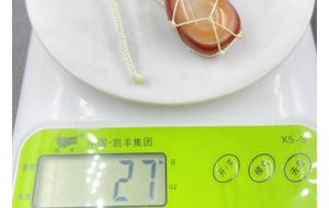 Macro detail of natural red agate pendant in net pouch weighing 27g on electronic scale