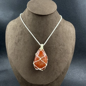 Red agate raw stone pendant necklace with hand-woven net cord on a jewelry neck display