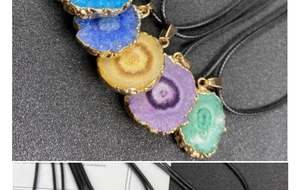 Detail of colorful natural agate slice pendants with electroplated gold edges and black cords