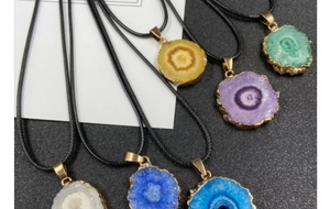Macro shot of colorful irregular druzy agate slices with gold plating on black cord necklaces