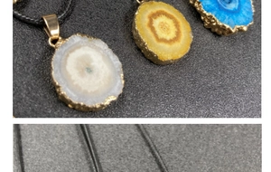Close-up of multicolored raw crystal flower pendants with gold plated edges on black cords