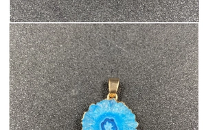 Macro detail of sky blue crystal pendant with raw texture and gold plated edges