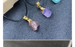 Detail view of raw amethyst and strawberry quartz pendants with gold-plated metal caps