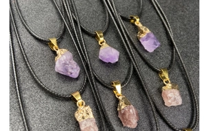 Group shot of raw amethyst and strawberry quartz crystal pendants with black wax cord