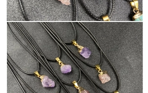 Detail of amethyst and rose quartz raw stone pendants with gold plating on black cord