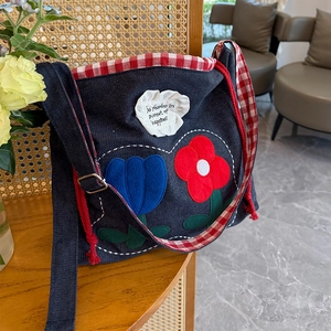 Detail of embroidered floral patch and grid strap on a casual denim crossbody bag