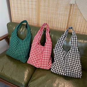 Retro plaid canvas tote bags in green, red and black displayed on a leather sofa
