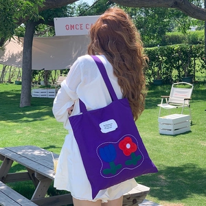 Detail of purple canvas tote bag with tulip embroidery during outdoor camping