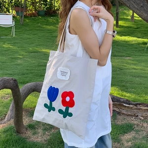 Shoulder bag detail featuring tulip embroidery and motivational text on nylon fabric