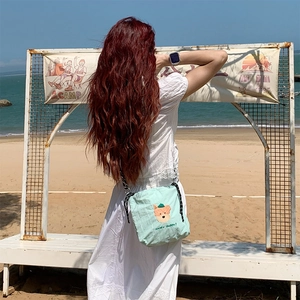 Détail du sac bandoulière en toile vert clair avec broderie chiot mignon sur une plage