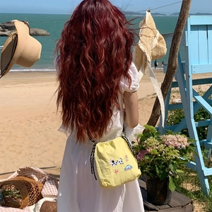 Détail d'un petit sac bandoulière jaune avec broderies mignonnes de chiot et champignon