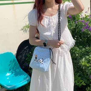 Détail du sac bandoulière bleu clair avec broderie dalmatien et bandoulière tressée