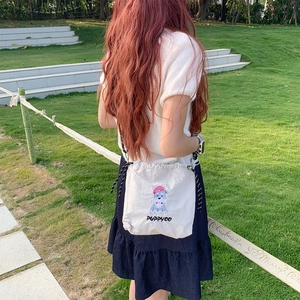 Détail du sac bandoulière en toile blanche avec broderie chiot et cordon de serrage rayé