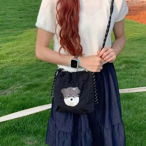 Vue détaillée du sac bandoulière couleur bonbon avec broderie chiot et sangle tressée