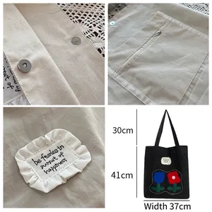 Minimalist black nylon tote bag with floral embroidery and magnetic closure detail