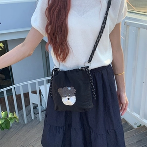 Détail du petit sac bandoulière noir en nylon avec broderie de chien et cordon serrage