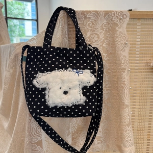 Detail of a black polka dot mini tote bag featuring a cute white plush puppy embroidery