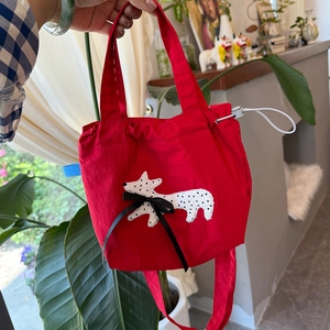 Detail of red canvas tote with cute fox embroidery and black ribbon bow accent