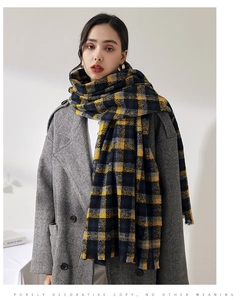 Detailed view of yellow and blue plaid scarf with fringes styled on a wool coat