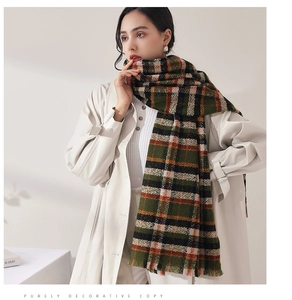 Detail of dark green plaid scarf with soft fringes and warm cashmere-like texture