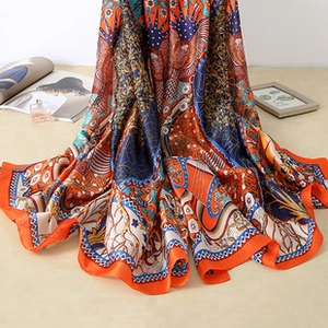 Close-up of exotic patterned satin scarf with orange borders and floral bird prints
