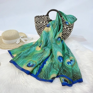 Close-up of silk scarf with peacock feather print on a woven basket and straw hat
