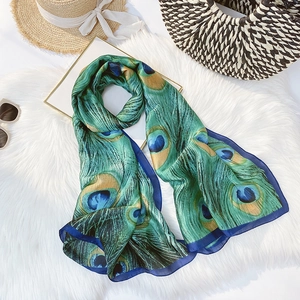 Close-up of vibrant peacock feather print silk scarf with semi-transparent texture