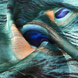 Macro detail of silk scarf featuring vibrant peacock feather pattern with glossy finish