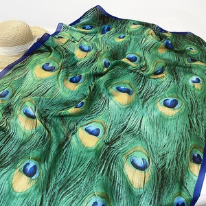 Detailed close-up of peacock feather silk scarf with elegant green and blue satin texture