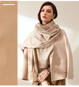 Close-up of beige plaid scarf fabric with tassels paired with a wool coat for autumn