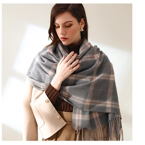 Detail of grey and pink plaid scarf with soft fringe texture for autumn and winter