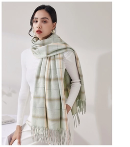 Close-up of soft plaid scarf with long tassels in light green and orange check pattern