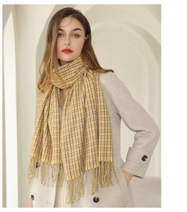 Détail de l'écharpe à carreaux jaune avec franges montrant la texture douce du cachemire