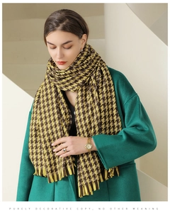 Detail of yellow and brown houndstooth scarf with fringe on dark green cashmere coat