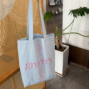 Bolso tote azul claro grocery con letras rojas y estampados botánicos de compra