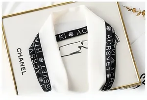 Close-up of a French style silk scarf with ACRSVET lettering and rose floral logo