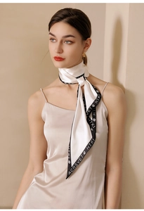 Detail of silk skinny scarf with contrast border and rose emblem tied on a neck