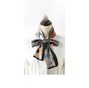 Détail d'un foulard en soie à imprimé abstrait noué en boucle sur une chemise blanche
