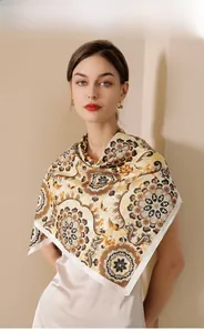 Detailed view of floral paisley pattern on silk-like scarf with warm beige tones