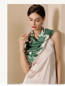 Detail of elegant dark green silk scarf with white floral print on model in beige top