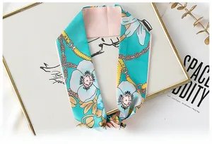 Detail of blue silk ribbon scarf showing white floral patterns and gold chain texture