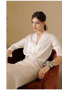 Close-up of a floral silk scarf tied around the wrist with a satin white v-neck shirt