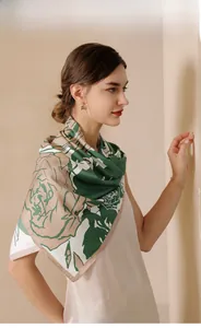 Close-up of elegant floral print silk scarf featuring dark green and beige artistic pattern