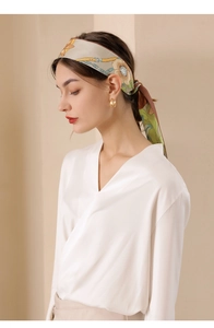Detailed view of floral silk scarf styled with a white blouse and gold jewelry