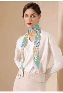 Close-up of light green floral silk scarf with lily prints and golden chain patterns