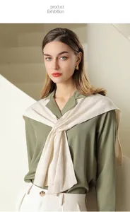 Nahaufnahme eines eleganten cremeweißen Strickschals über einer salbeigrünen Seidenbluse