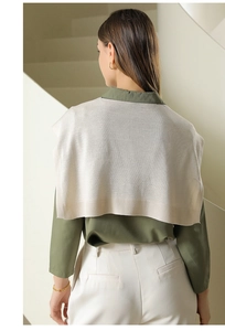 Detail showing layers of a dark green shirt paired with a beige knit shawl wrap