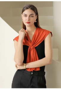 Detail of soft orange knitted shawl layered over black sleeveless knit top on model